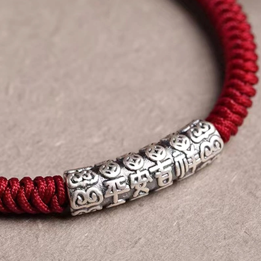 Sterling silver rope bracelet with protective blessing charm on brown wooden background