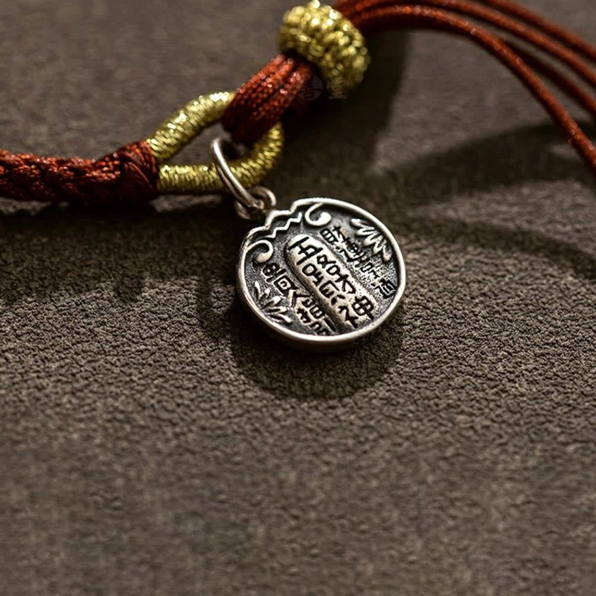 Close-up detail of 925 sterling silver wealth charm with engraved Chinese characters and protective knot