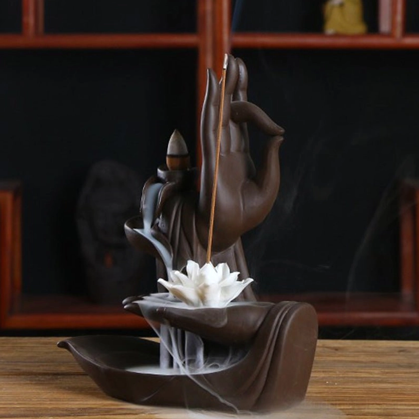 Buddha hand incense burner with white lotus, burning stick incense with flowing aromatic smoke on wooden shelf display