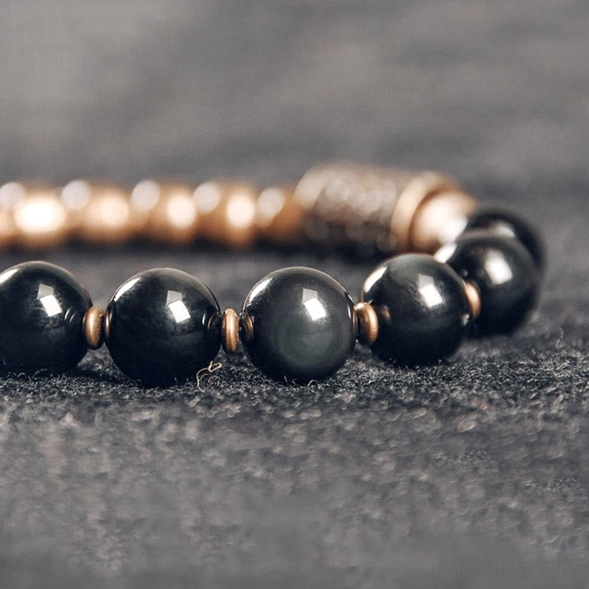 Lava rock and obsidian stone beads with brass spacer, close-up showing natural mineral patterns and craftsmanship