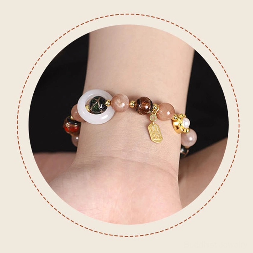 Sun stone Buddhist prayer wheel bracelet with golden beads and spiritual blessing metal tag, top-down view