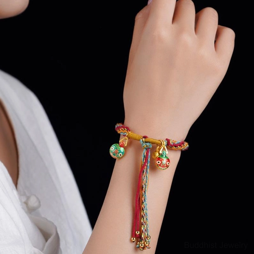 Woman wearing gold swallowing beast braided string bracelet on wrist with tassel pendants, demonstrating proper fit and wearing position