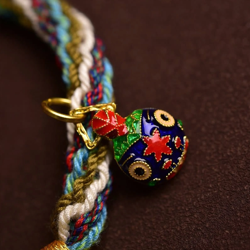 Cloisonné enamel Swallowing Beast charm with gold clasp and colorful Buddhist patterns macro close-up