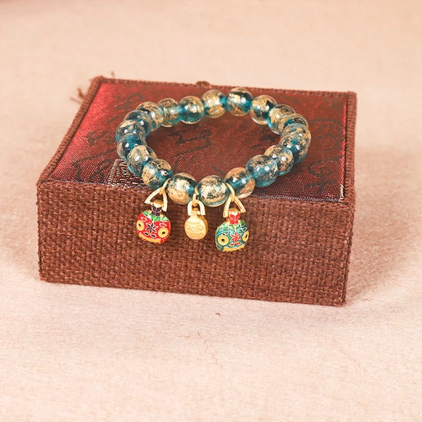 Gold Swallowing Beast family Buddhist prosperity bracelet three-quarter view showing teal round beads with dangling gold enamel charm pendants