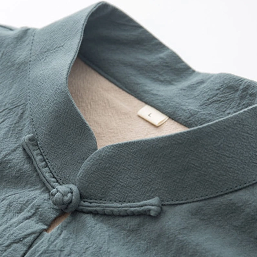 Detailed close-up of teal linen tang suit neckline with size tag and traditional frog button knot craftsmanship