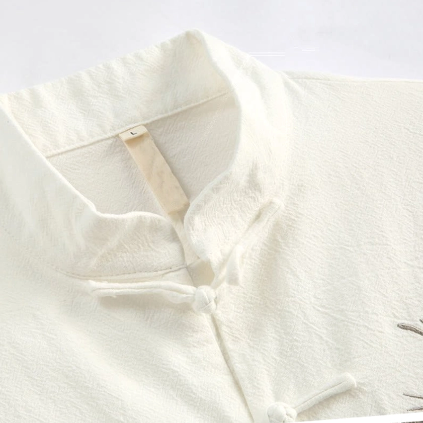 Close-up detail of Tang suit stand collar and traditional frog button closures with linen texture