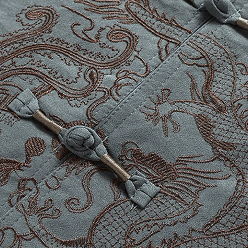 Detailed close-up of dragon embroidery and frog button on grey Tang suit with premium fabric weave