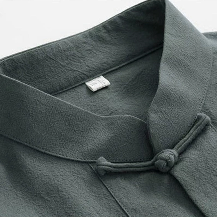 Close-up of Tang suit stand collar with traditional frog button and inner size tag on dark green linen fabric