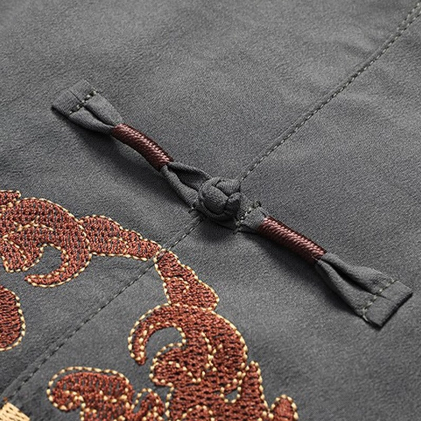 Hand-crafted brown woven frog button closure detail on dark gray Tang suit fabric, showing traditional Chinese knot fastener