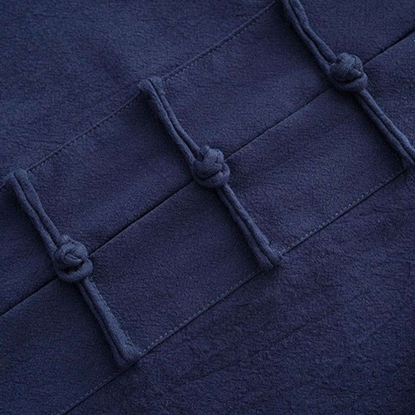 Detailed close-up of hand-knotted frog button on navy blue Tang suit fabric
