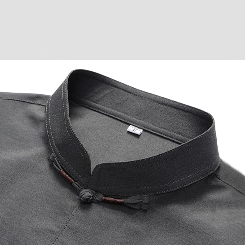 Close-up detail of Tang suit mandarin collar and frog button fastener on dark gray fabric, showcasing traditional Chinese closure technique