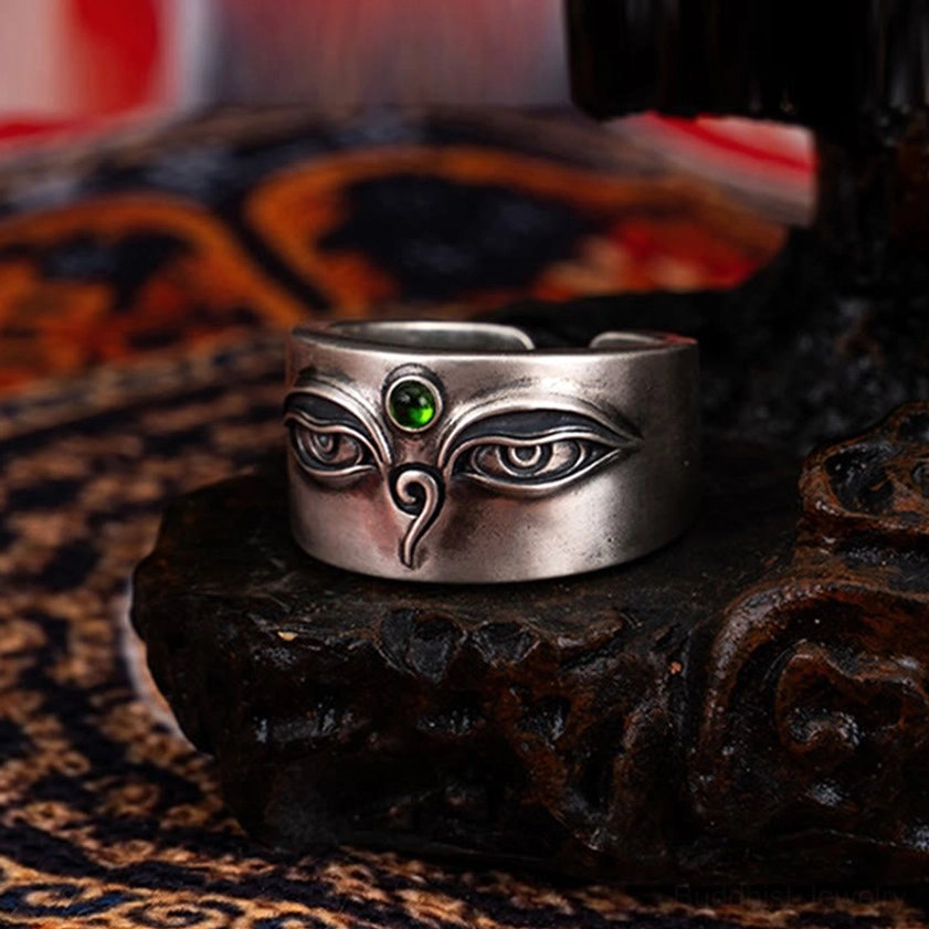 Polished 925 sterling silver Tara Buddhist ring with engraved sacred eye pattern and vibrant green stone inlay on carved wooden base