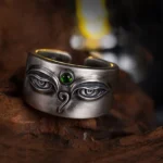 925 sterling silver Bodhisattva Tara adjustable ring with hand-engraved eye motif and green gemstone, displayed on antique wooden platform showing front top-down view