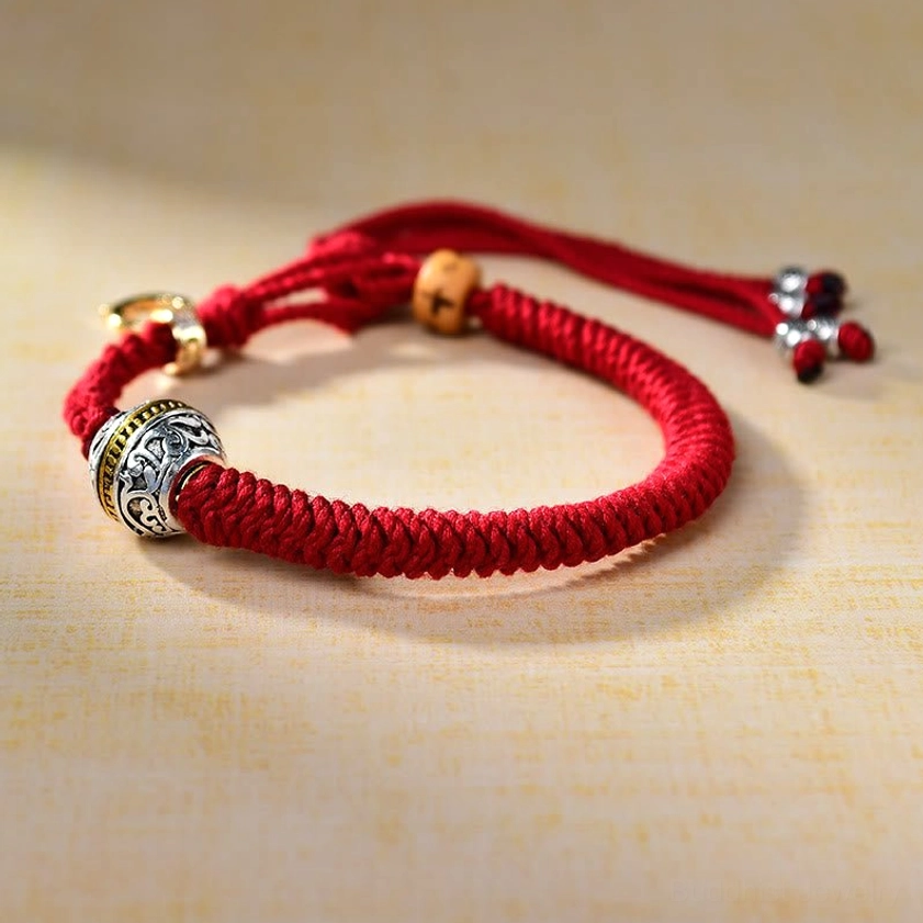 Green Tara Buddhist red string bracelet with ornate silver bead and fastener detail, left angle view