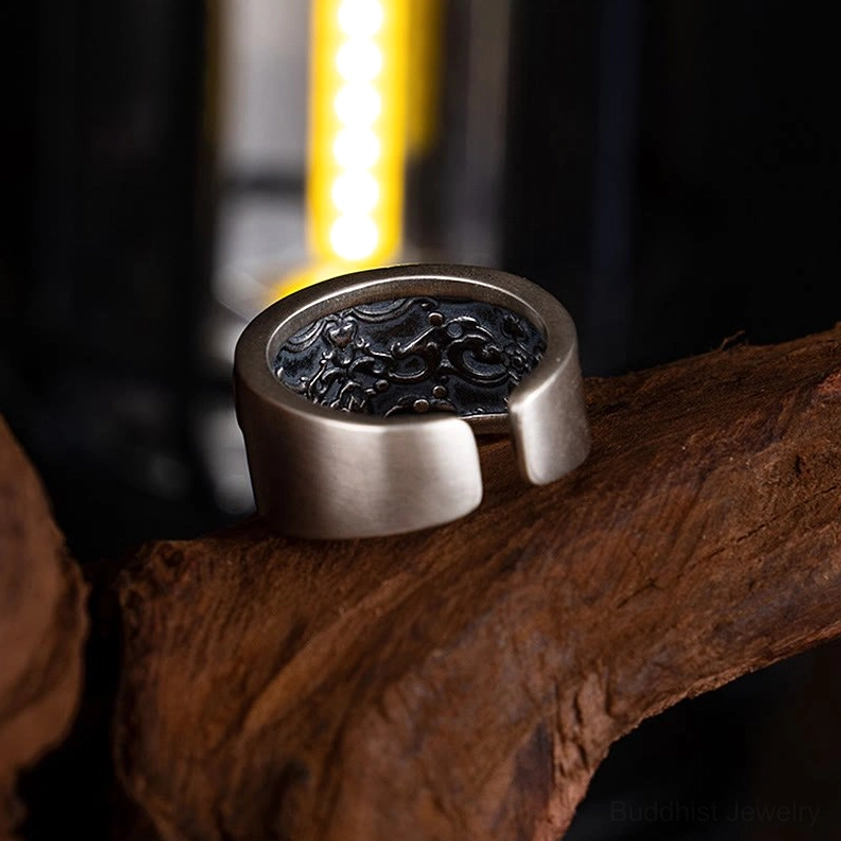 Inner band of Tara adjustable ring displaying intricate carved spiritual patterns and antique silver finish on wooden branch display stand