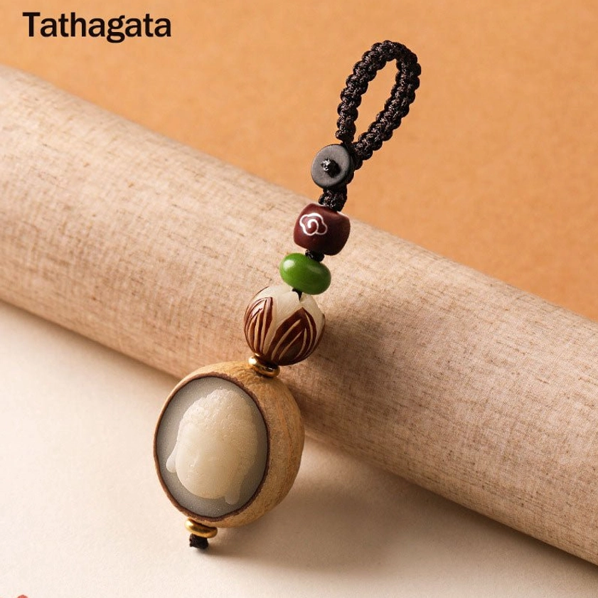 Tathagata Buddha carved bodhi seed keychain with natural shell details and braided rope attachment