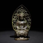 Tathagata Buddha alloy statue frontal view with antique bronze patina and hollowed floral backboard on dark background