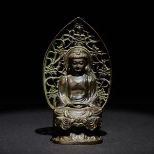 Tathagata Buddha alloy statue frontal view with antique bronze patina and hollowed floral backboard on dark background