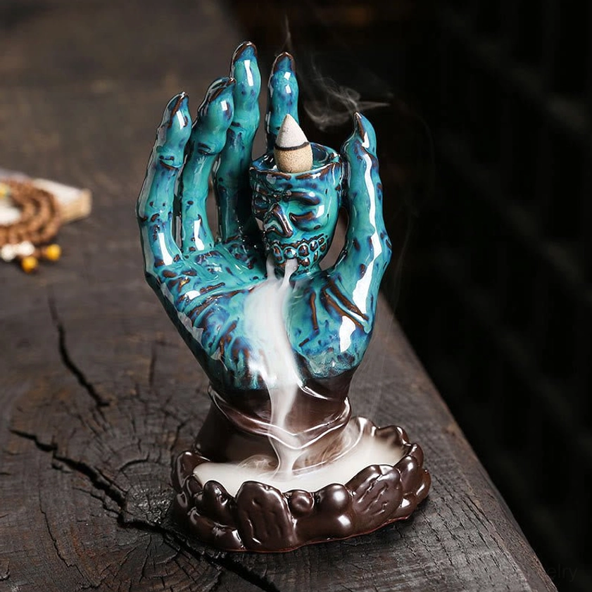 Teal blue two-tone ceramic skull hand backflow incense burner with brown base and cascading smoke