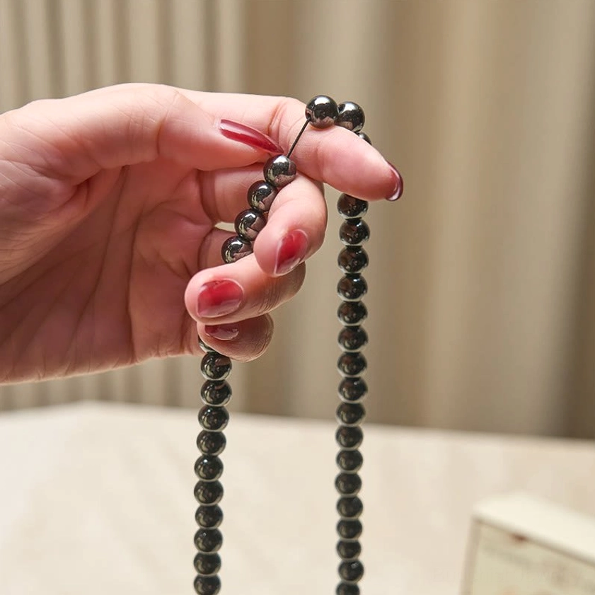 Terahertz 108 bead mala held by hand with red nail polish, hanging prayer bead strand with smooth polished surface