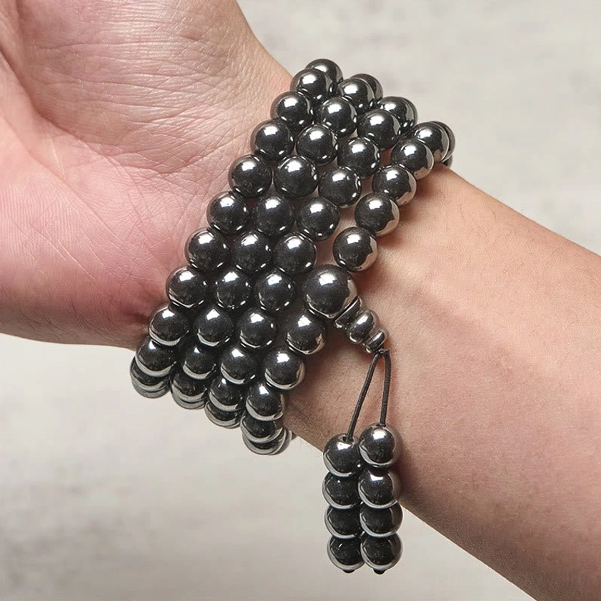 Terahertz mala worn on wrist lifestyle shot, coiled beads on human wrist with dangling tassel and dark metallic finish