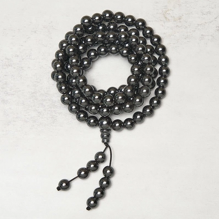 Terahertz Buddhist prayer mala overhead close-up, polished dark gray beads centered loop with matching tassel detail