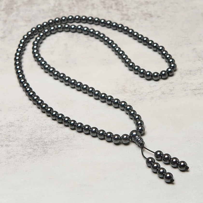 Terahertz 108 bead mala necklace fully extended on minimalist light surface, uniform round beads with bead tassel charm