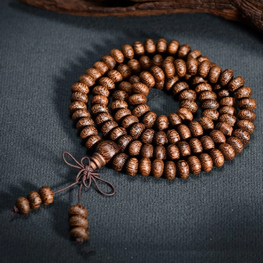 Compact coiled natural wood bead mala with distinct grain patterns and decorative tassel knot