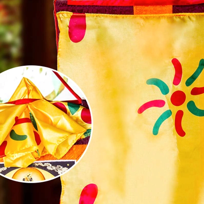 Thangka brocade top decoration detail showing yellow satin fabric with red and green ornamental patterns