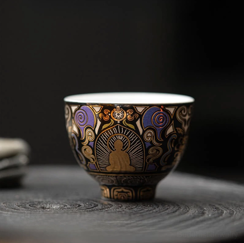 Symmetrical Buddhist auspicious cloud design on ceramic tea cup placed on dark wooden tabletop, showcasing spiritual patterns