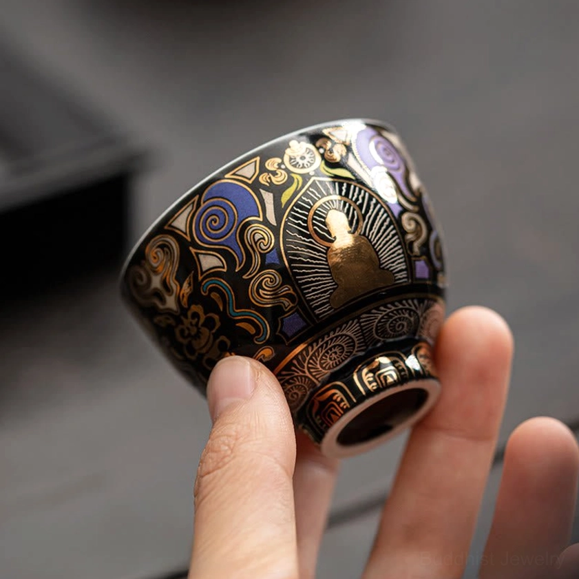 Side bottom oblique view of hand-held Buddhist tea cup displaying clear pattern details and crafted cup foot against dark blurred backdrop