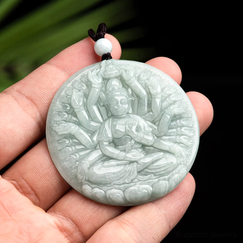 Thousand-hand Kwan Yin jade pendant held in hand showing scale and size, light green natural jade with compact round carving and white accent bead