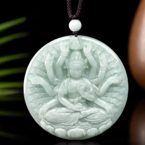 Thousand-hand Avalokitesvara jade pendant displayed on decorative prop with green foliage, showing intricate carving detail on light green natural jade with black wax cord and white jade bead