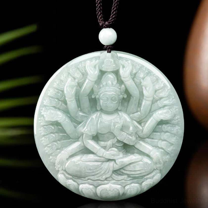 Thousand-hand Avalokitesvara jade pendant displayed on decorative prop with green foliage, showing intricate carving detail on light green natural jade with black wax cord and white jade bead