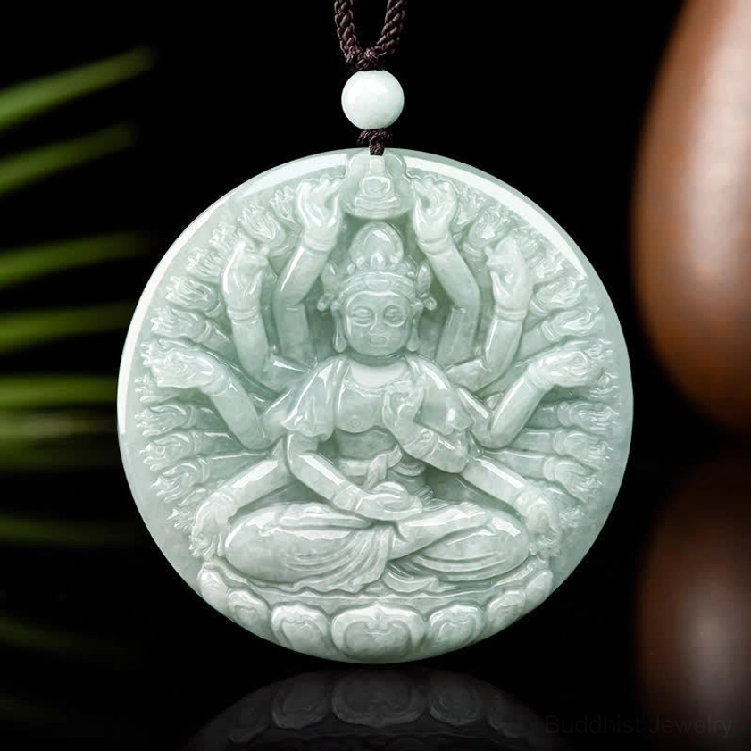 Thousand-hand Kwan Yin jade pendant frontal view with green foliage and brown prop background, complete thousand-hand Guanyin relief carving in light cyan jade