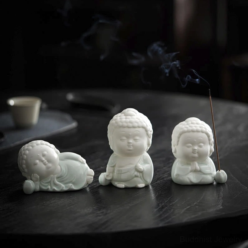 Set of three handcrafted Buddha incense burners - one reclining and two seated poses with burning incense on wooden tea table