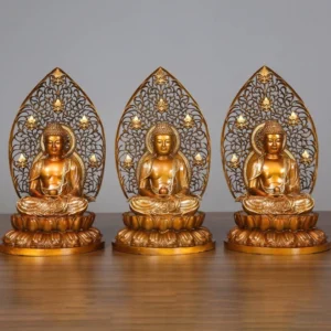 Three handcrafted copper Buddha statues displayed together on wooden table - Sakyamuni Amitabha and Medicine Buddha figurines with ornate lotus bases