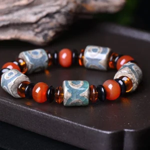 Three-eye Dzi bead agate bracelet overhead flat lay on wooden tray, showing vintage distressed pattern and natural agate craftsmanship