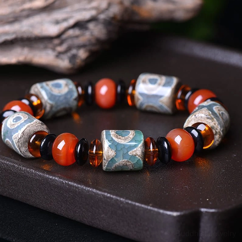 Three-eye Dzi bead agate bracelet overhead flat lay on wooden tray, showing vintage distressed pattern and natural agate craftsmanship