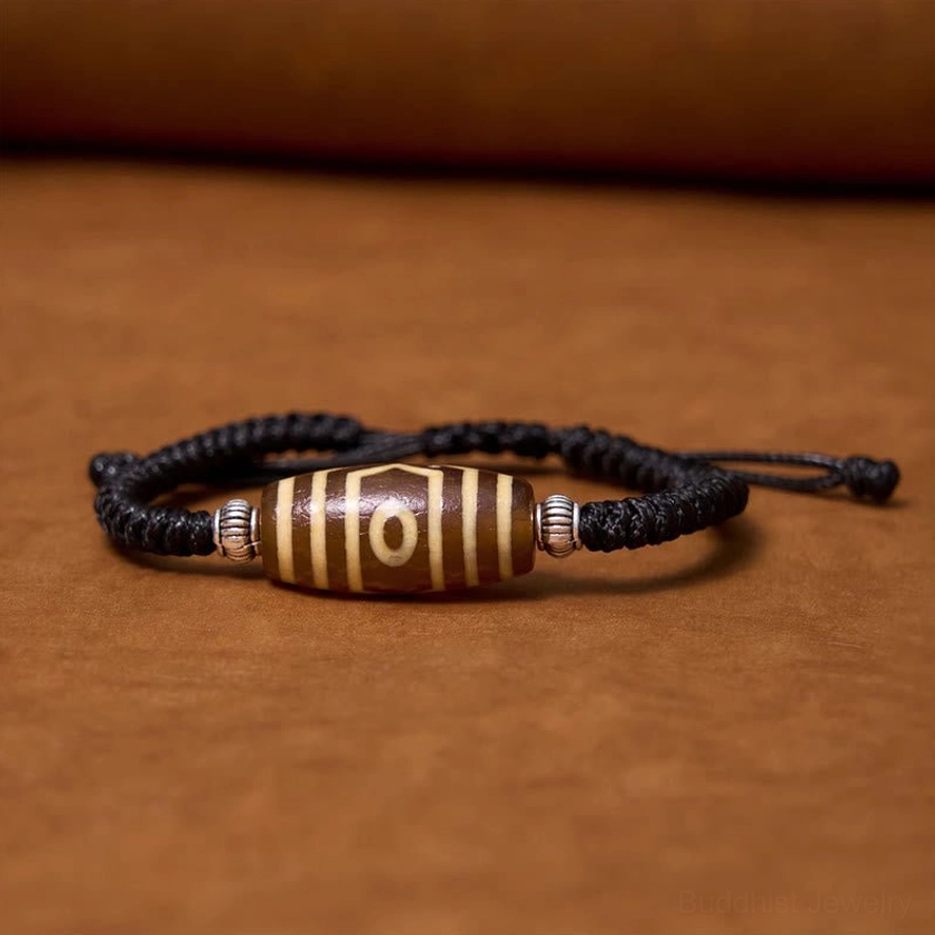 Three-eye dzi bead bracelet detailed front view highlighting sacred three-eye design and metalwork
