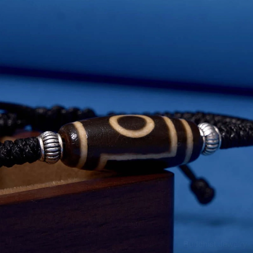 Three-eye dzi bead bracelet worn on wrist demonstrating comfortable adjustable fit and real-world wear appearance