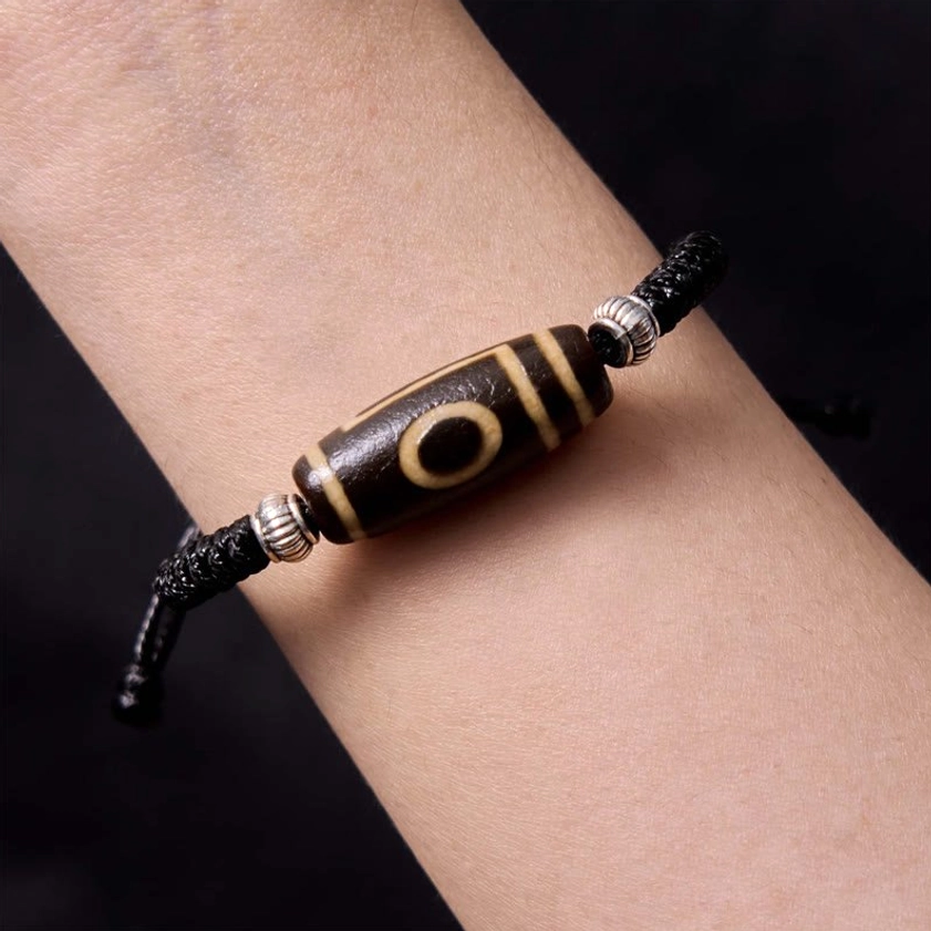 Three-eye dzi bead bracelet side detail view showing hand-painted three-eye motif and silver metal accents