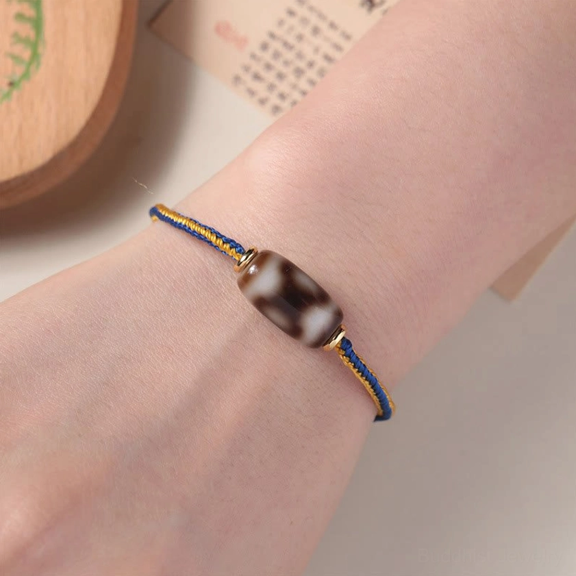 Three-eye Dzi bead bracelet worn on human wrist showing proper fit and adjustable cord design