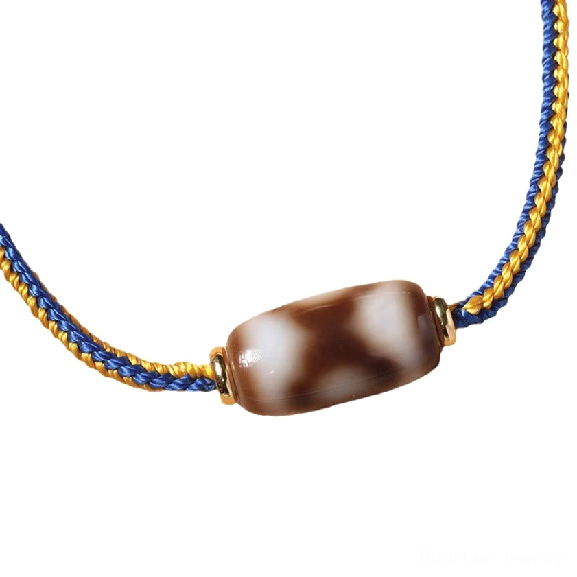 Full length three-eye Dzi bead bracelet flat lay top-down view with braided cord and single dzi bead centerpiece