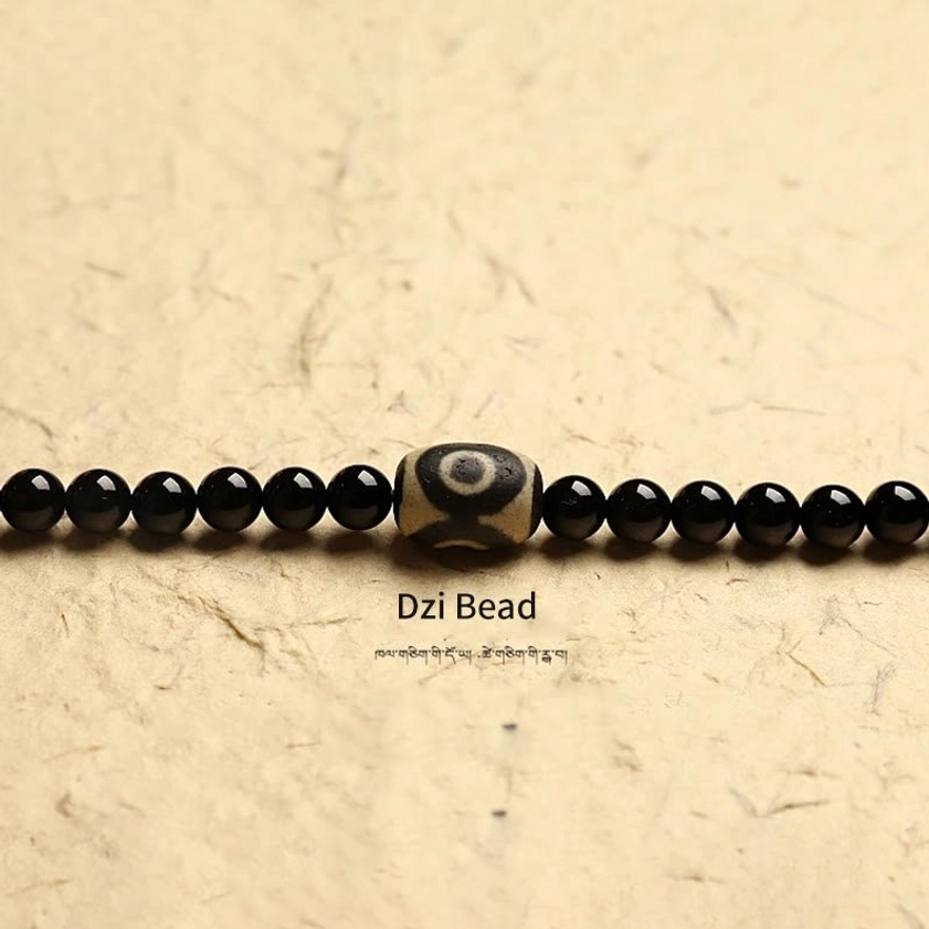 Macro close-up of three-eyed dzi bead with black onyx beads showing sacred symbolic patterns