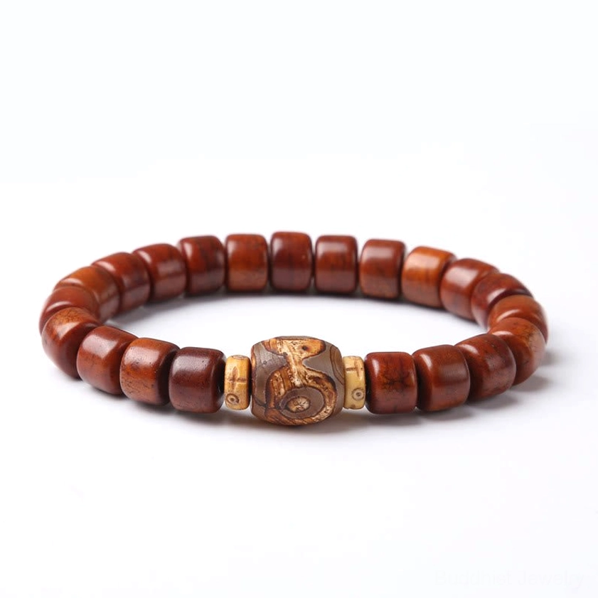 Three-eyed Dzi bone bead bracelet flat lay top view with carved dzi focal bead on white background