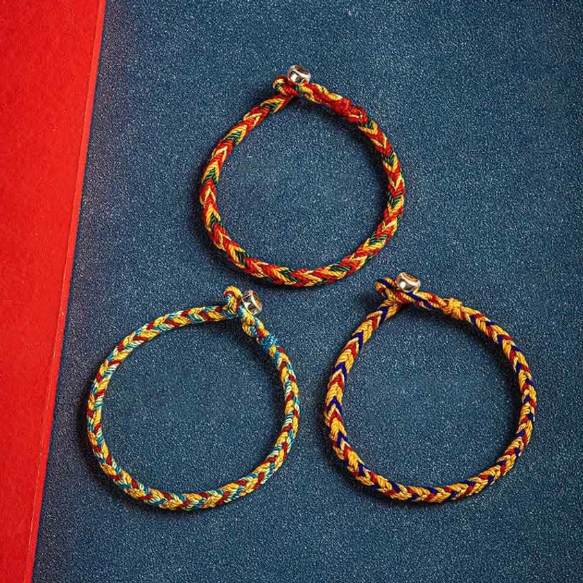 Three matching handwoven multicolored Buddhist protection bracelets arranged in flat lay, displaying consistent braided design and silver charms