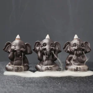 Three elephant backflow incense burners in handcrafted purple clay with cascading smoke effect, front flat lay view on dark studio background