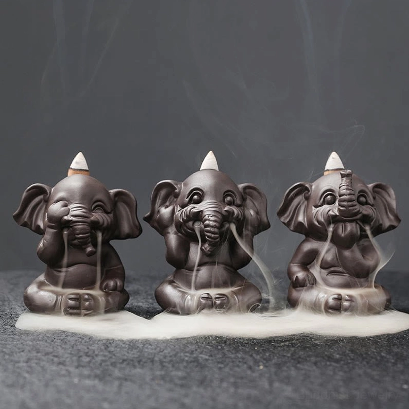 Three elephant backflow incense burners in handcrafted purple clay with cascading smoke effect, front flat lay view on dark studio background