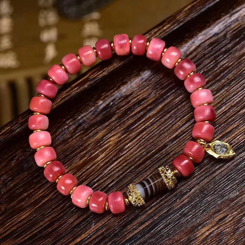 Tibetan Buddhist bracelet with striped dzi bead and camel bone red agate beads wooden desk